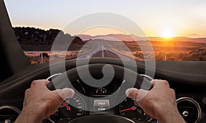 Driving at sunset. View from the driver angle while hands on the wheel photo