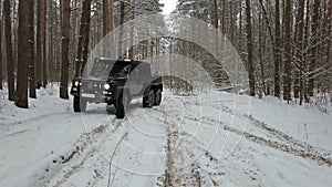 Driving SUV 6x6 by the off-road in the winter forest, front left view