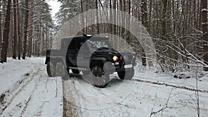 Driving SUV 6x6 by the off-road in the winter forest, front view right