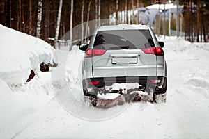 Driving SUV car in winter on forest snow road