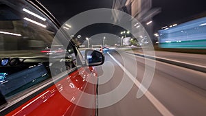 Driving urban look from fast driving car at a night avenue in a city