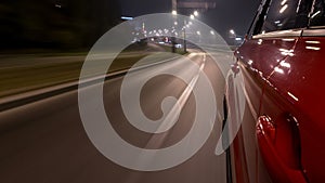 Driving urban look from fast driving car at a night avenue in a city