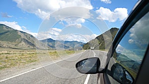 Driving view from side of car mirror mountain gorgeous valley. Beautiful landscape of a road in the mountains on sunny