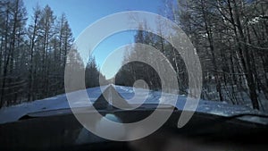 Driving through the winter forest on snowy road