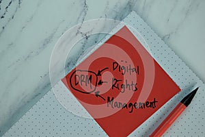 DRM - Digital Rights Management write on sticky note isolated on Wooden Table