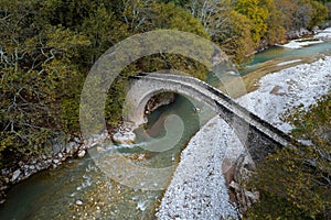 Drone aerial of ancient, stoned , arched bridge on the Portaikos river in autumn. Trikalla pyli village Thessaly Greece