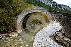 Drone aerial of ancient, stoned , arched bridge on the Portaikos river in autumn. Trikalla pyli village Thessaly Greece