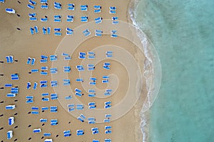 Drone aerial of beach chairs in a tropical sandy beach. Summer holidays in the sea.