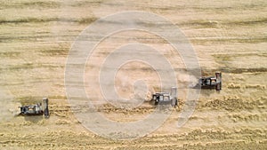 Drone aerial footage of harvesters gathering grain crops from agricultural fields