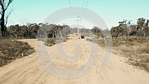 Drone aerial footage of telephone lines along a dirt road in regional Australia