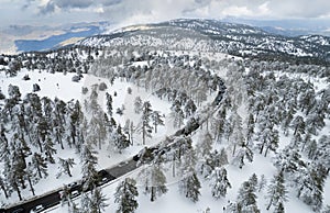 Drone aerial of highway road on the snowy forest mountain in winter.