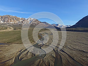 Drone aerial image of twisting, winding, streams in a fluvial river valley in northeast Greenland