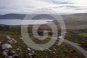 Drone aerial panoramic view of a camper van in green and red landscape with atlantic ocean in Tourinan Cape in Galicia, Spain