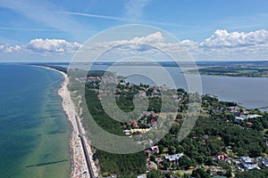 Drone Aerial Perspective View on Touristic City Located on narrow Spit between Sea and Lake with sunbathers on sand beach