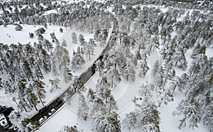 Drone aerial scenery of highway road crossing the snowy mountain forest landscape in winte