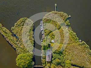 Drone aerial scenery of a lake with boat moored on the lake side. Aerial view of lake landscape with small fishing boats at the e