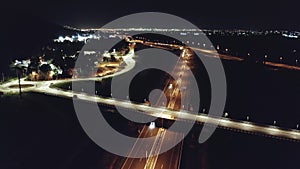 Drone aerial shot of night traffic on a highway showing cars and lanes of light with bridges and viaducts