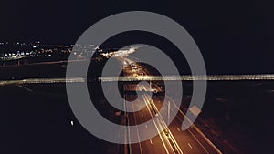 Drone aerial shot of night traffic on a highway showing cars and lanes of light with bridges and viaducts