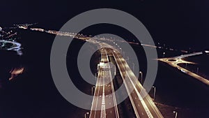 Drone aerial shot of night traffic on a highway showing cars and lanes of light with bridges and viaducts