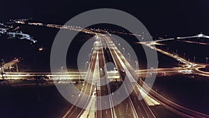 Drone aerial shot of night traffic on a highway showing cars and lanes of light with bridges and viaducts