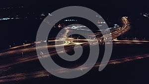 Drone aerial shot of night traffic on a highway showing cars and lanes of light with bridges and viaducts