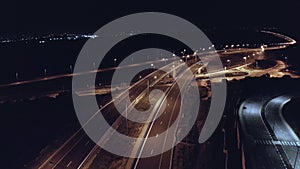 Drone aerial shot of night traffic on a highway showing cars and lanes of light with bridges and viaducts