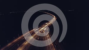 Drone aerial shot of night traffic on a highway showing cars and lanes of light with bridges and viaducts