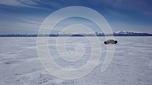 Drone aerial view of car in winter landscape and hi speed driving over the frozen lake.
