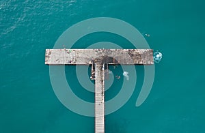 Drone aerial view of people diving in the sea from a jetty. Healthy lifestyle. People swimming in the ocean