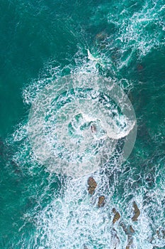 drone aerial view of ocean waves breaking against rocks on the coastline