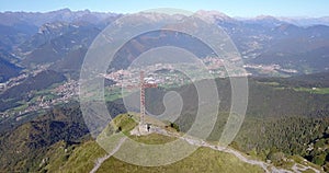 Drone aerial view to the Seriana valley and Orobie Alps in a clear and blue day. The cross at the top of the mountain