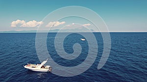 Drone aerial view of two white boats sailing through the sea in a beautiful sunny weather with Mt Athos in the