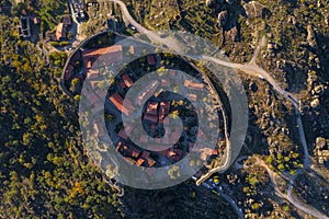 Drone aerialtop above view of Sortelha historic village at sunset with lights on the castle eolic wind turbines and nature