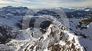 Drone ascending over a mountain ridge covered with snow. Dolomites, Italy