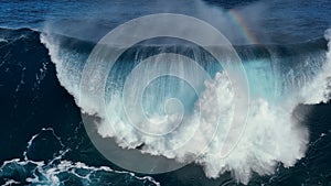 Drone barreling wave with texture and wind spray. Aerial shot of breaking surf with foam in Pacific Ocean. Powerful