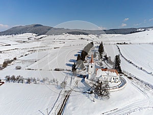 Drone camera flying over a small catholic church at wintertime in Transylvania
