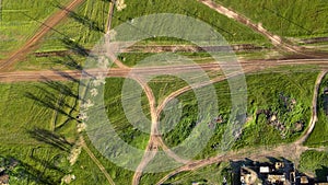 Drone with camera rotates, rising above the ground. Green fields dotted with lines of rural roads, rare forest belt and