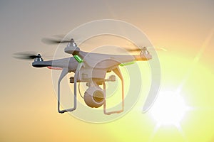 Drone with camera on sunset background