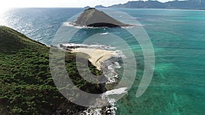 drone camera vertical pan, white waves braking on the beach of green island in open waters, color graded