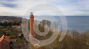 A drone captures Gaski beach, West Pomeranian Voivodeship, Poland, featuring a red brick lighthouse, Baltic Sea, sandy shore,