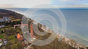 A drone captures Gaski beach, West Pomeranian Voivodeship, Poland, featuring a red brick lighthouse, Baltic Sea, sandy shore,