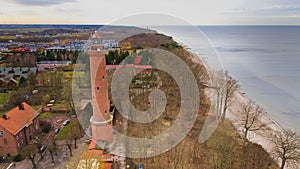 A drone captures Gaski beach, West Pomeranian Voivodeship, Poland, featuring a red brick lighthouse, Baltic Sea, sandy shore,