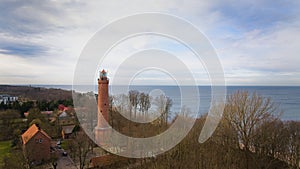 A drone captures Gaski beach, West Pomeranian Voivodeship, Poland, featuring a red brick lighthouse, Baltic Sea, sandy shore,