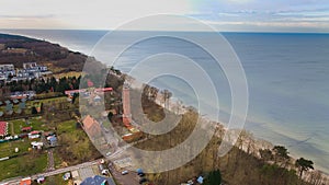 A drone captures Gaski beach, West Pomeranian Voivodeship, Poland, featuring a red brick lighthouse, Baltic Sea, sandy shore,