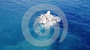 Drone captures lonely cliff amidst tranquil sea waves, highlighting serene interaction between wave and lonely cliff set