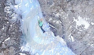 DRONE: Woman carefully placing her ice axes while climbing up an icy waterfall