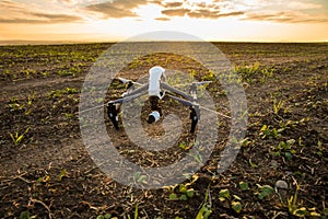 Drone with digital camera flying in sky over field on sunset