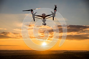 Drone with digital camera flying in sky over field on sunset