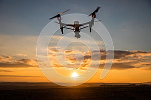 Drone with digital camera flying in sky over field on sunset