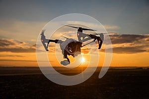 Drone with digital camera flying in sky over field on sunset